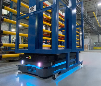 Black robot with blue light carrying a blue metal frame in a warehouse