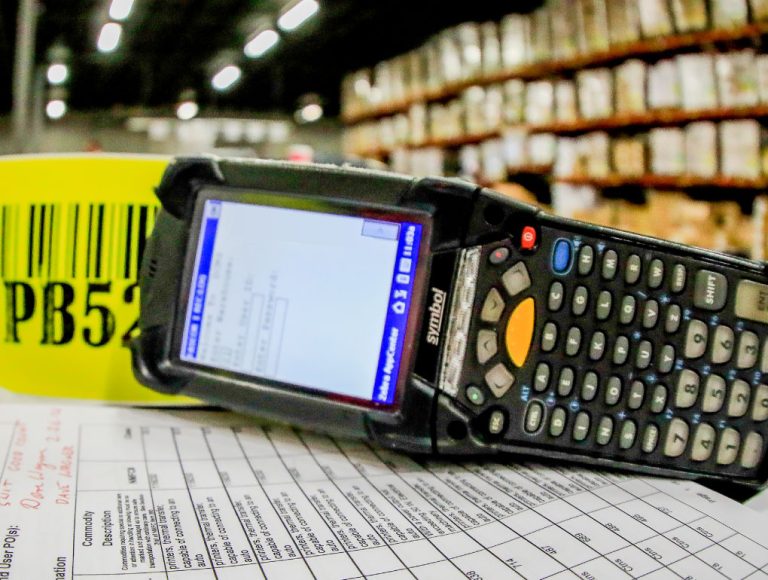 Black barcode scanner with keypad in front of yellow barcode tag
