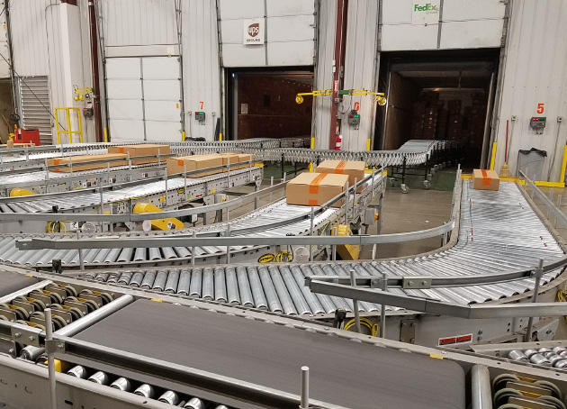 Boxes moving down conveyors into shipping area in warehouse