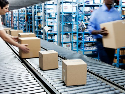 Men grabbing boxes from conveyor in fulfillment warehouse