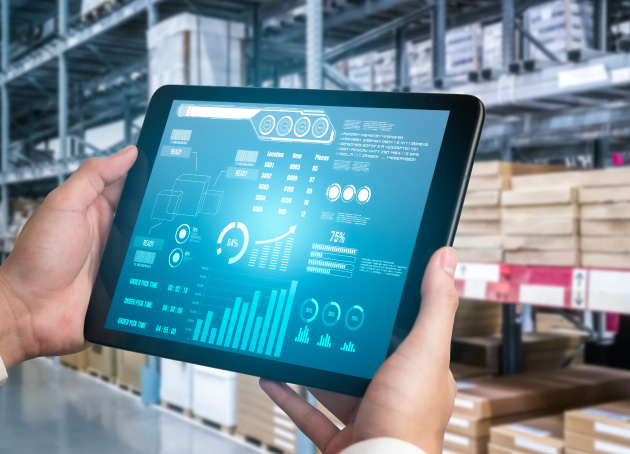 Person holding tablet with data dashboard in front of warehouse shelving